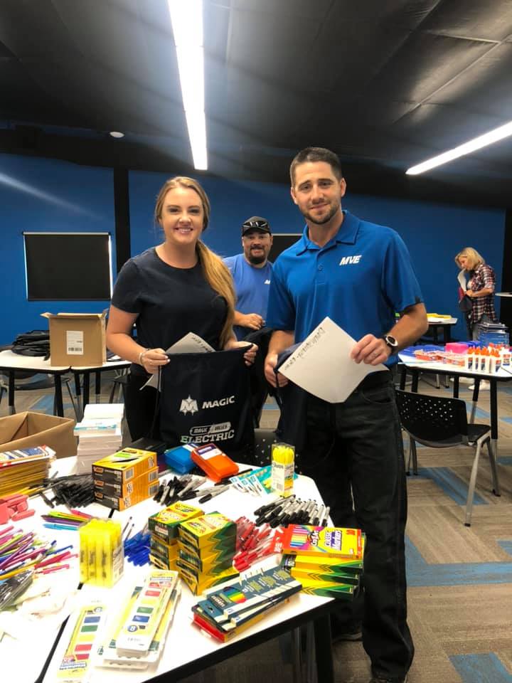 A Magic Valley Electric LLC with a member of a local charity receiving art supplies